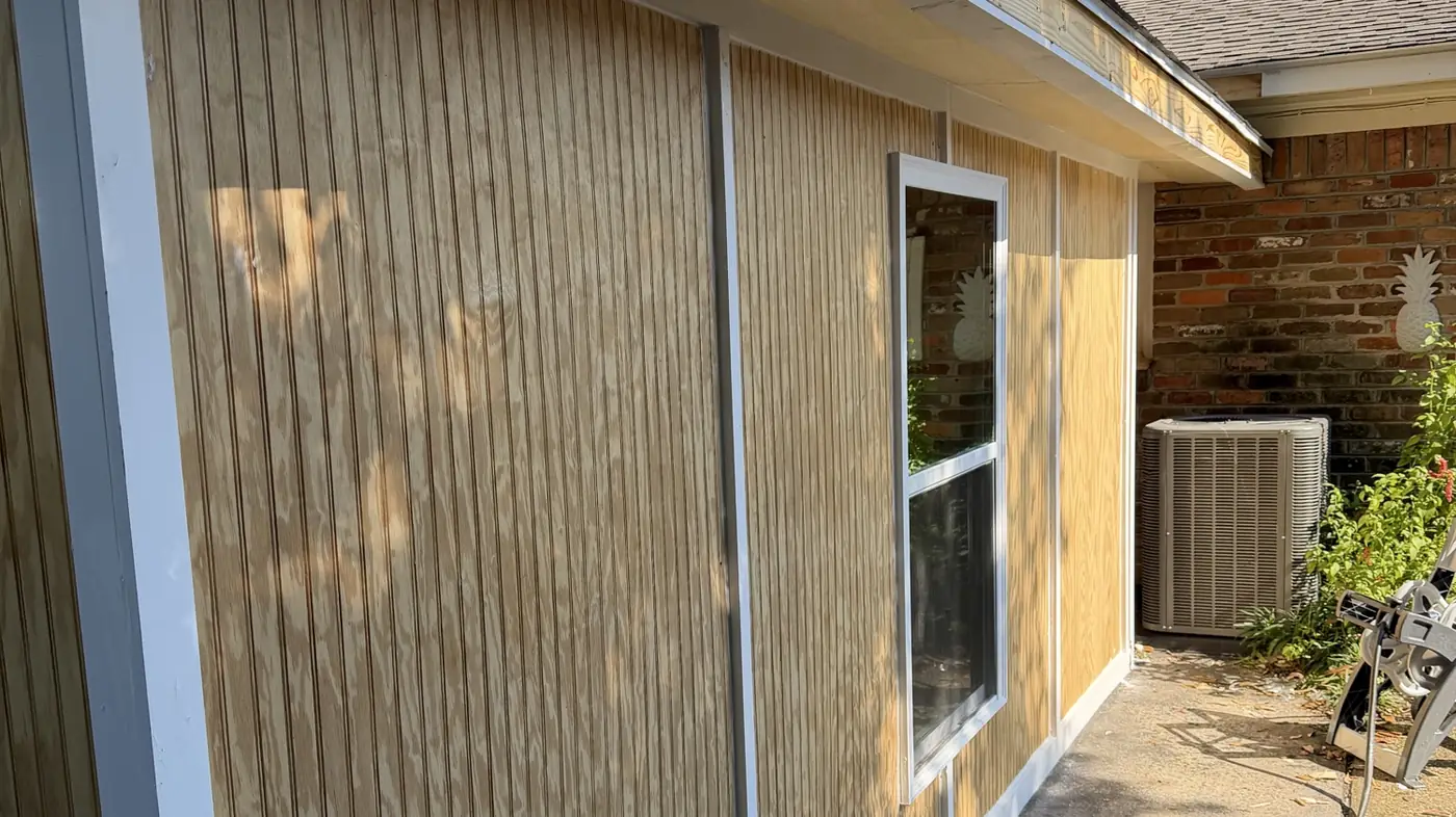 Side elevation of the enclosure showing new siding, a new window and crisp white trim against the original brick