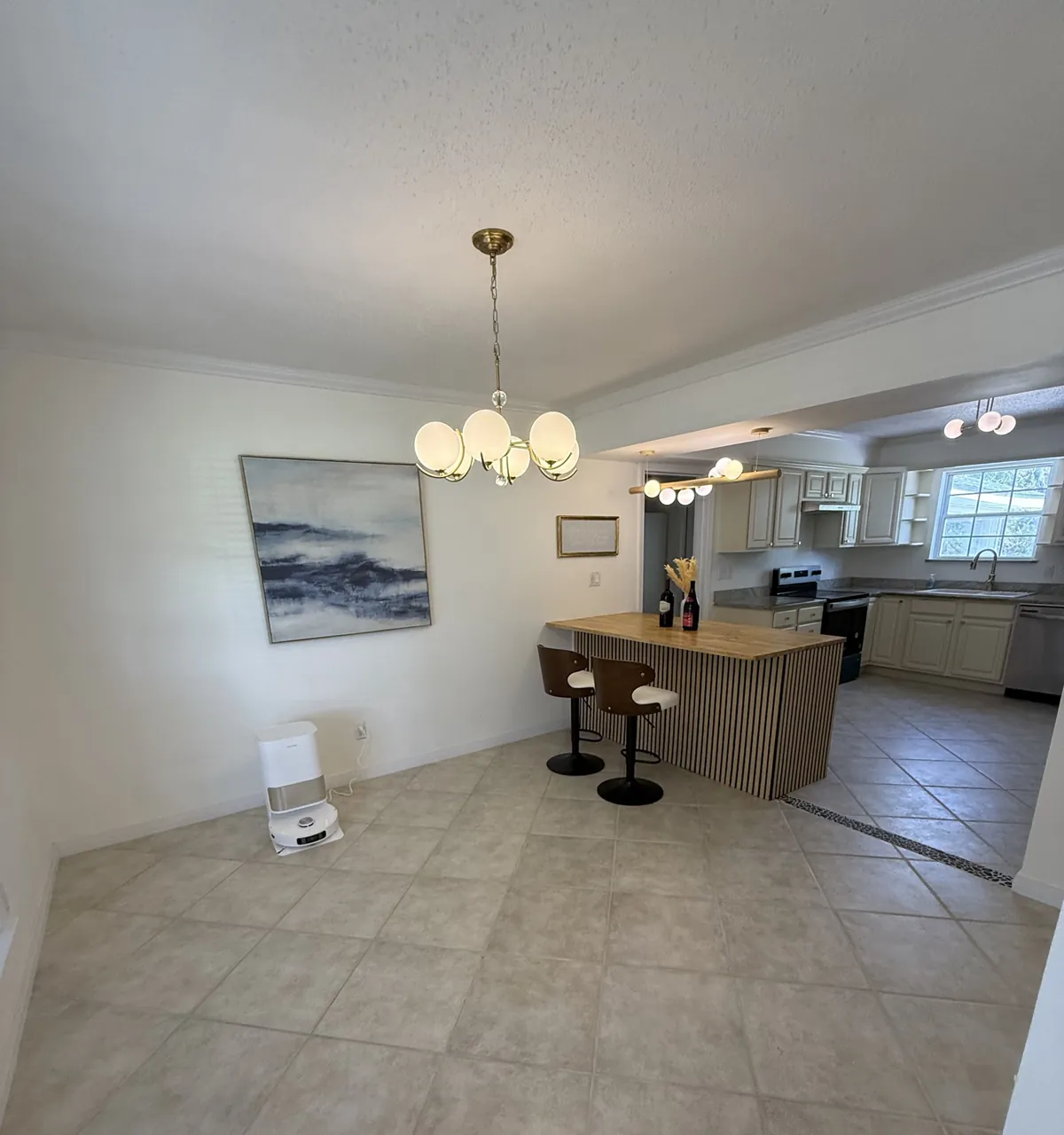 Dining area opening into the kitchen with a slat-front bar, butcher block top, brass globe lighting and tile flooring