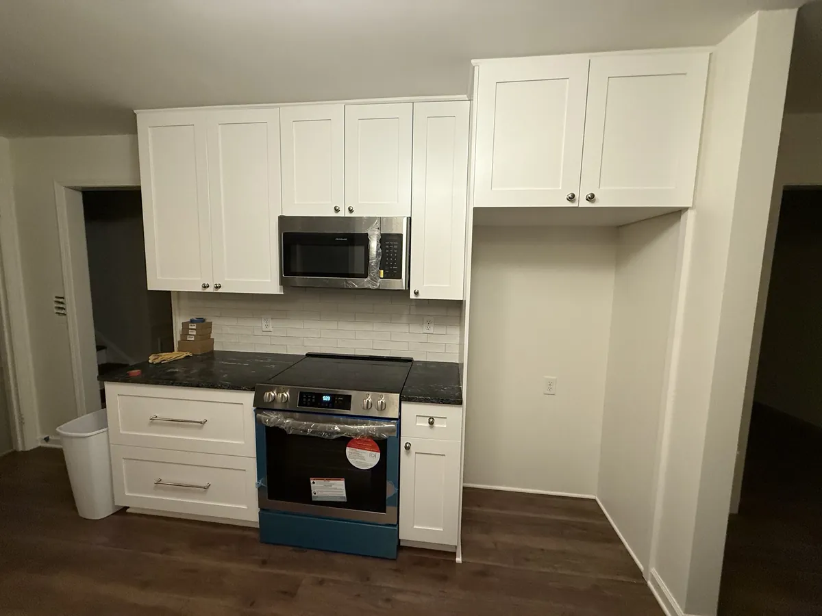 Kitchen range wall with a stainless slide-in range, over-range microwave, white subway tile and black granite counters